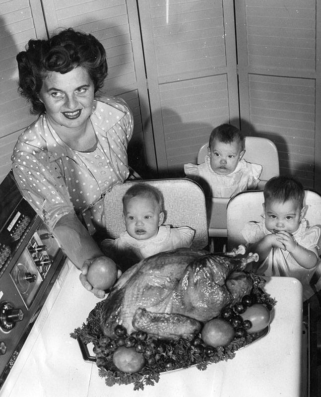  Thanksgiving Day full of meaning for ex-Russian. Triplet daughters of Mr. and Mrs. Edwin Agner, 11219 Elkwood Ave., Sun Valley, celebrate their first Thanksgiving. Nine-month-old girls surround their mother as she puts finishing touches on turkey taken piping hot from electric range. November 26, 1959. Order #00114456
