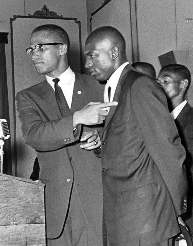 Photograph was taken at Park Manor Auditorium, 607 S. Western Ave., Los Angeles. Malcolm X is shown indicating wound the unidentified man suffered after the clash between police officers and the Muslim men, May 21, 1962. Photo by Jeff Goldwater
